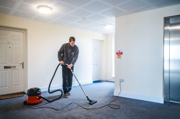 Communal area cleaning being carried out in a residential building corridor to maintain a clean and safe shared space.