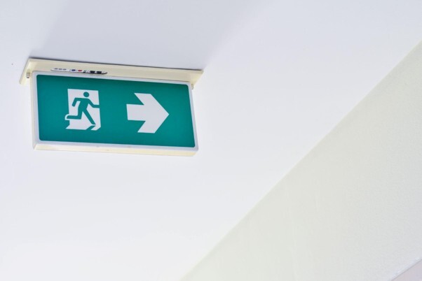 Testing emergency lights in a residential block, shown by an illuminated emergency exit sign.